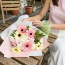 A bouquet of pink and white gerbera daisies and carnations with a pink ribbon.