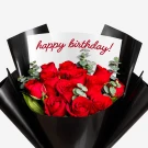 A bouquet of 12 red roses with eucalyptus, wrapped in black paper, with "happy birthday!" written on a card.