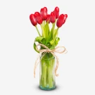 Red tulips in a glass vase with a twine bow.