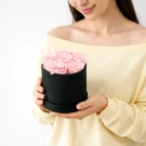 Woman holding black box with pink preserved roses.