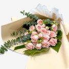 Pink spray roses and eucalyptus in a soft cream and parchment paper bouquet.