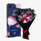 Bouquet of red and white roses, violet statice, and eucalyptus leaves in black paper with a gift box.