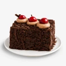 Chocolate cake with chocolate shavings, whipped cream, and cherries on top.