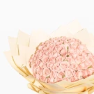 99 blush pink roses in a light brown paper bouquet wrapper, against a white background.