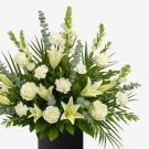 White lilies, roses, carnations, and matthiola in a funeral arrangement.
