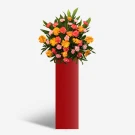 Bright orange and pink flowers in a red stand, symbolizing optimism and success.