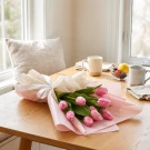 Pink tulips bouquet wrapped in pink and white paper with a white ribbon.