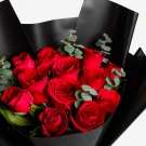 Bouquet of 12 red roses with eucalyptus and ruscus, wrapped in black paper.