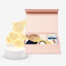 Pink gift box with teddy bear lamp and self-care items.