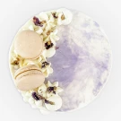 Round Earl Grey Lavender cake with white frosting swirls, macarons, and edible flowers.
