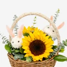 Woven basket with sunflowers, white mum bunnies, and greenery.