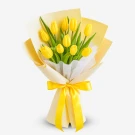 A bouquet of 10 bright yellow tulips with green leaves, wrapped in cream and yellow paper, tied with a yellow ribbon.