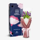 A bouquet of purple tulips with patterned wrapping sits next to a dark blue box with floral designs.