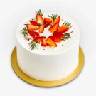 White frosting cake topped with sliced strawberries and rosemary sprigs on a gold cake board.