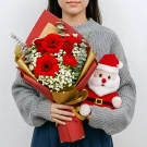 Woman holding a red Gerbera daisy and rose bouquet and a plush Santa Claus toy.