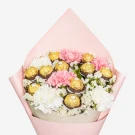 Bouquet of pink and white carnations interspersed with gold-wrapped chocolates, wrapped in pale pink paper.