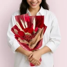 Woman in white shirt holding a red and tan dried flower bouquet with roses and wheat.