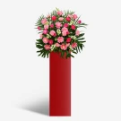 A tall red stand with a large bouquet of pink and fuchsia flowers and green foliage.