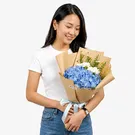 Bouquet of blue hydrangeas, white carnations, and asters with "Thank You" topper.