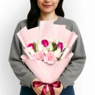Woman holding a pink bouquet with white and pink roses and carnations.