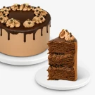 Chocolate cake with chocolate frosting, ganache drip, and piped frosting decorations, with a slice on a separate plate.