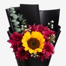 Sunflower with deep maroon mums and eucalyptus, wrapped in black paper.