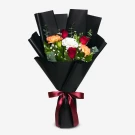 Bouquet of red roses, white and two-toned yellow carnations, and white phoenix flowers, wrapped in black paper and tied with a red ribbon.