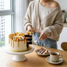 Slice of chocolate cake with white frosting, caramel drizzle, and orange slices.