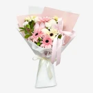 Pink and cream gerbera daisies and white mums in a bouquet wrapped in pink and white paper with pink and cream ribbons.