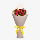 Bouquet of six red roses wrapped in taupe paper and tied with a yellow ribbon.