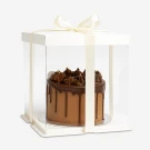Chocolate crunch cake in a clear gift box with a cream ribbon bow.