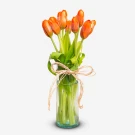 Red-orange tulips in a clear glass vase, tied with twine.