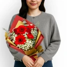 Woman holding a red gerbera daisy and rose bouquet with baby's breath and eucalyptus.