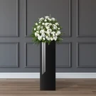 A white floral arrangement on a tall black stand.
