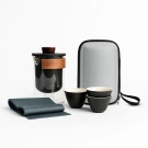 Tea set with glass jug, wooden band, three cups, and carrying case.