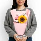 Woman holding a pink bouquet with a large sunflower and pink carnations.
