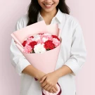Woman holding a bouquet of red, pink, and white carnations in pink wrapping.