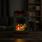Christmas village in a gift box with red ribbon and lights.