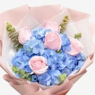 Bouquet of pink roses and blue hydrangeas with eucalyptus, wrapped in pink and white paper.