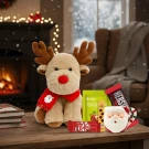 Reindeer plush with Santa mug, KitKat, Hershey's bar, and a power bar in front of a fireplace.