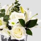 White roses, lilies, and daisies with greenery in a vase.