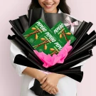 Woman holding a bouquet of Lotte Pepero Almond chocolate sticks wrapped in black paper and pink tissue.