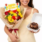 Woman holds a bright bouquet of flowers, a birthday card, and a chocolate cake.