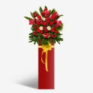 Red floral arrangement with roses, anthuriums, gerberas, mums, and carnations in a red vase.