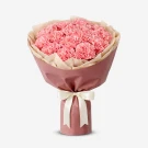 Pink carnation bouquet wrapped in rose paper with a cream ribbon.