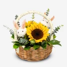 Wicker basket with sunflowers, white chrysanthemums shaped like bunnies, and greenery.