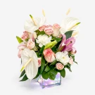 Pink roses, white anthuriums, and lilies in a iridescent cube vase.