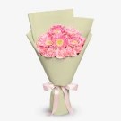 Pink gerberas and carnations bouquet wrapped in light green paper with pink ribbon.