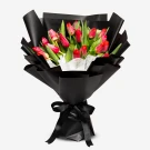 Bouquet of 20 red tulips in black paper wrap, tied with a black ribbon bow.