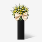 Yellow and white flowers with a large tan bow on a black stand.